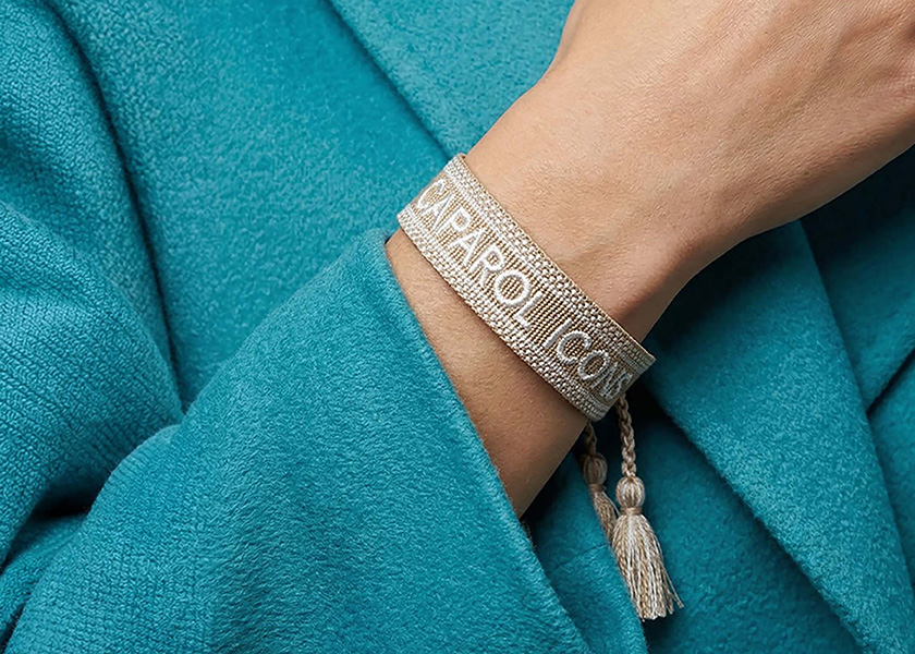 Specialbroderat vävt canvasarmband med företagsnamn, tillverkat på beställning av en leverantör av reklamprodukter.