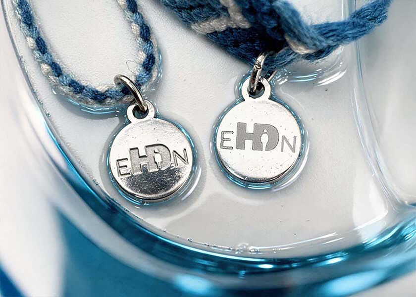 Hellblaues geflochtenes Freundschaftsarmband mit rundem Logo-Charm als individuell gestaltbares Werbegeschenk