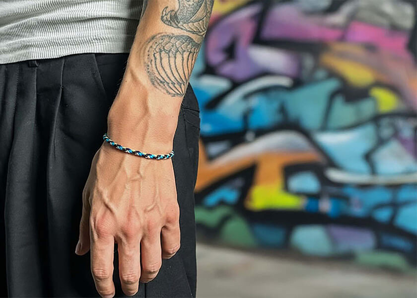 Blaues geflochtenes Freundschaftsarmband mit Logo-Charm auf bedruckter Karte als individuelles Merchandise-Produkt