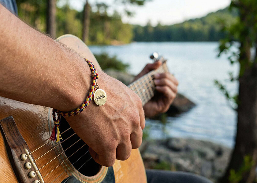 Rotes geflochtenes Freundschaftsarmband mit Logo-Charm auf bedruckter Karte als individuelles Merchandise-Produkt